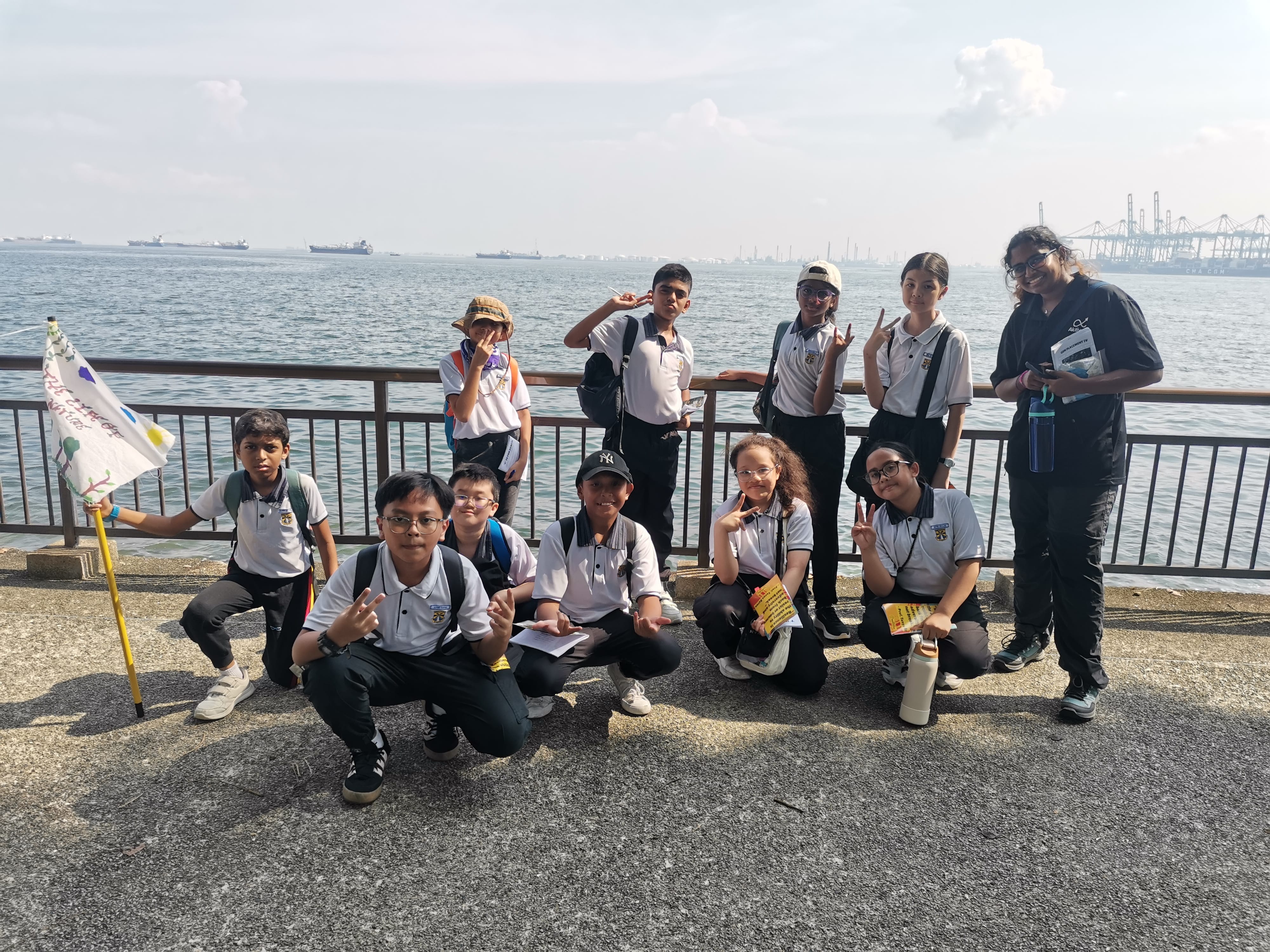 Flag held high for a waterfront group photo, container ships included.